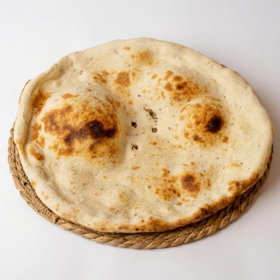 Round, lightly charred flatbread served on a woven basket plate against a plain white background.